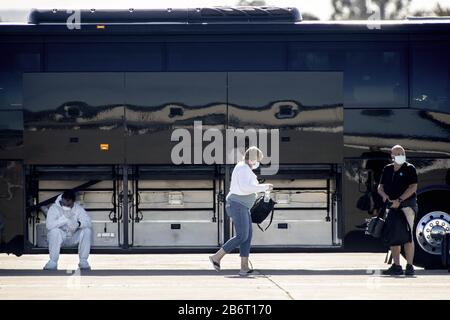 Oakland, Vereinigte Staaten. März 2020. Eine Transportarbeiterin macht eine Pause, nachdem sie Passagiere und ihr Gepäck am Mittwoch, den 11. März 2020, von einem Bus des Kreuzfahrtschiffs Grand Princess unterstützt hat, um ein gechartertes Flugzeug am Oakland International Airport in Oakland, Kalifornien zu starten. Foto von Peter DaSilva/UPI Credit: UPI/Alamy Live News Stockfoto