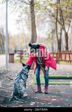 Mädchen, die mit ihrem Hund im Herbstpark spielen Stockfoto