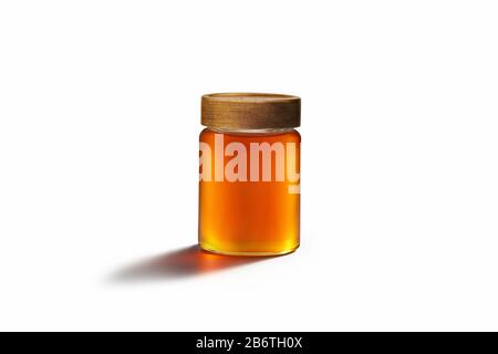 Frischer Honig mit Holzdeckel auf einem Glasbehälter. Folgen des zentralen dominanten Gesetzes im Hintergrund des Whitepapers. Stockfoto