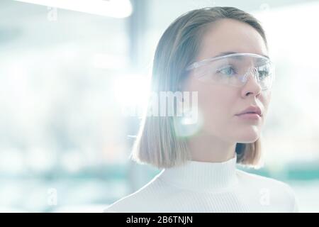 Nachdenkliche, attraktive junge Frau, die Informationen mit einer intelligenten Brille analysiert, Linsenflauscheffekt Stockfoto