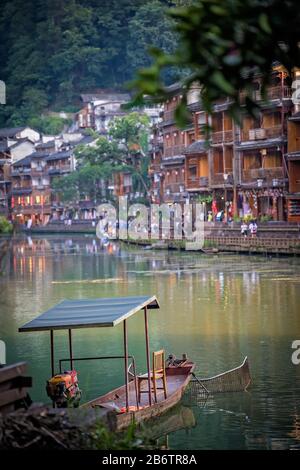 Feng Huang, China - August 2019: Alte vernachlässigte Holzboot historische Diaojiao-Häuser am Ufer des Flusses Tuo, die durch das Zentrum von Fen fließen Stockfoto