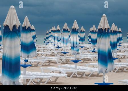 Back-end am Strand. Sonnenschirme wurden geschlossen, der Zauber des schönen Wetters ist gebrochen. Stockfoto