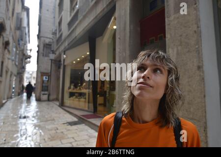 Touristen in der Altstadt. Reisender mit hellorangefarbenem T-Shirt und kleinem Rucksack. Stockfoto