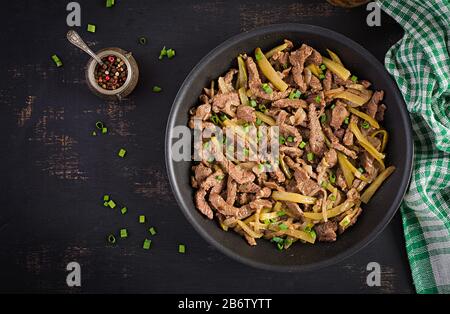 Einstechen Sie Rindfleisch, in Sojasoße mit Gewürzen mit eingepickter Gurke im asiatischen Stil gedünstete Fleischstücke. Draufsicht, oben, flach Stockfoto