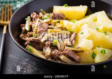 Einstechen Sie Rindfleisch, mit eingelegten Gurken bestücktes Rindfleisch im russischen Stil. Rinderstroganoff und gekochte Kartoffeln. Stockfoto