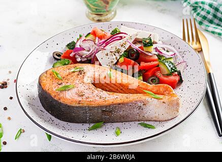 Ketogenes Mittagessen. Gebackener Lachs mit griechischem Salat garniert. Gesundes Abendessen. Keto/Paläo-Diät. Stockfoto