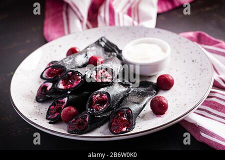 Süße Pfannkuchen mit Ricotta und Kirschen. Schwarze Pfannkuchen. Frühstück. Stockfoto