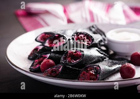 Süße Pfannkuchen mit Ricotta und Kirschen. Schwarze Pfannkuchen. Frühstück. Stockfoto