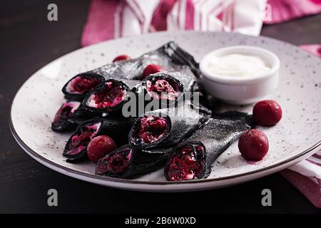 Süße Pfannkuchen mit Ricotta und Kirschen. Schwarze Pfannkuchen. Frühstück. Stockfoto