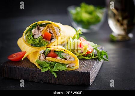 Frische Tortilla-Wraps mit Huhn und frischem Gemüse auf Holzbrett. Hühnerburrito. Mexikanische Küche. Kopierbereich Stockfoto