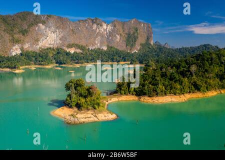 Luftaufnahme der winzigen Finger des tropischen Regenwaldes, der sich in einen riesigen See erstreckt, der von hoch aufragenden Kalkfelsen umgeben ist (Khao Sok) Stockfoto