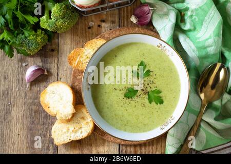 Vegetarisches Gericht. Köstliche Brokkoli Creme-Suppe mit Knoblauchkroutonen auf einem rustikalen Tisch. Flacher Laienhintergrund in der Draufsicht. Stockfoto