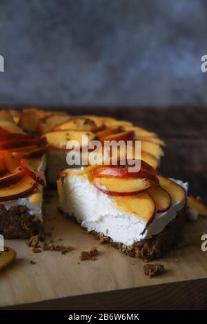 Hausgemachter Käsekuchen mit Pfirsichen. Gesundes Fruchtdessert mit Frischkäse, Nektarinen, Honig und Thymian auf Holzbrett. Diät-Kuchen Stockfoto