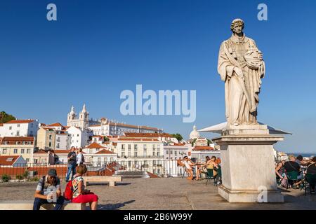 Touristen und Statue von Sao Vicente am Aussichtspunkt Largo das Portas do Sol und Blick auf alte Gebäude im historischen Viertel Alfama in Lissabon. Stockfoto