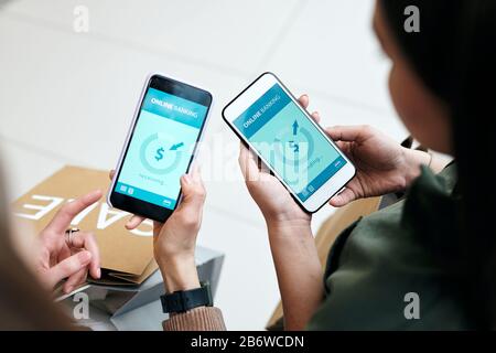 Über der Ansicht, dass Frau, die online mit einer mobilen Bank Geld an Freunde schickt, auf Gadgets zugeht, sie gemeinsam einkaufen Stockfoto