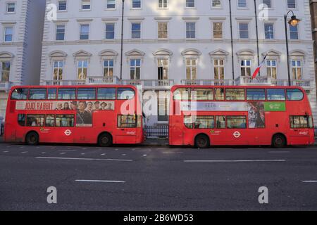 Zwei rote Doppeldeckerbusse werden außerhalb der unter Denkmalschutz stehenden Gebäude abgestellt, die von der Schule Lycée Francais Charles de Gaulle in der Cromwell Road, London, Großbritannien, genutzt werden. Stockfoto