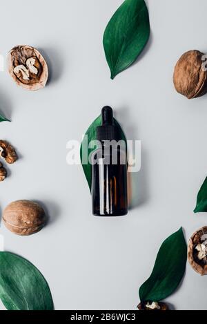Das Konzept der natürlichen Inhaltsstoffe in der Kosmetik. Kosmetik- und Heilöl aus Nussbaum auf weißem Grund. Natürliche Seren. Flache Lage, Draufsicht. Schön getönt. Stockfoto