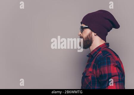 Seitenansicht des hübschen bärtigen Hüftmännchens in violetter Kappe und Brille. Stockfoto