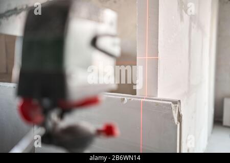 Der Bauarbeiter Misst Horizontniveau mit Laserniveau. Errichtung von Innenwänden in der Wohnung mit einer Betonplatte aus Putz Stockfoto