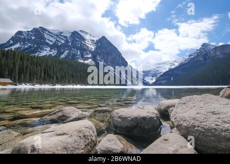 Mount fairview, teilweise gefrorener See, Felsen im Vordergrund. Lake Louise Banff National Park, Alberta Canada Stockfoto