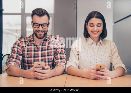 Fröhliche glückliche Kollegen schreiben Nachrichten auf Handys. Stockfoto