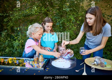 Kinder, die Lebensmittel untersuchen. Serie: Zubereitung von Blumenzehl. Getrocknete Blumen mit Zucker mischen. Lernen nach dem Reggio-Pädagogik-Prinzip, spielerisches Verständnis und Entdeckung. Deutschland. Stockfoto