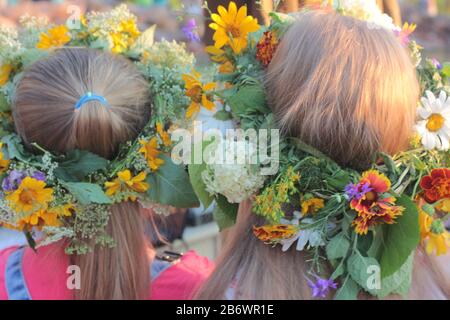 Zwei Mädchenköpfe in Kronen von Wildblumen, Nahaufnahme, Rückansicht. Ukrainischer Blumenkranz für Ivana Kupala auf dem Midsummer fest Stockfoto