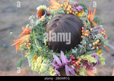 Kopf des Mädchens in einem Kranz aus Wildblumen, junge Frau in einem Blumenkränz, in der Nähe, Rückansicht. Hochsommerfeiern Kupala-Nacht in der Ukraine Stockfoto