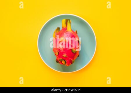 Pitaya. Die Nahaufnahme reifer Drachenfrucht auf Platte auf gelbem Grund. Stockfoto