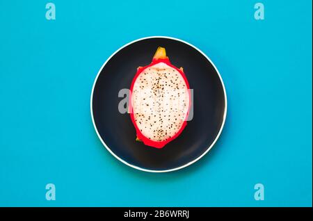 Pitaya. Die Nahaufnahme reifer Drachenfrucht auf Platte auf gelbem Grund. Stockfoto