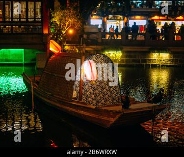 Traditionelles chinesisches Boot mit Papierlaternen und Lichtern in einem See in der Nacht Stockfoto