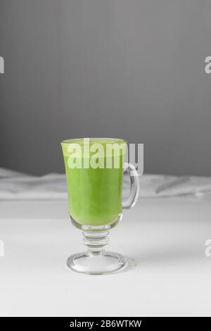 Grüne Latte in Glaskasse, Matchlatte mit Schaum auf weißem Tisch Stockfoto