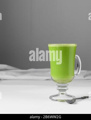 Grüne Latte in Glaskasse, Matchlatte mit Schaum auf weißem Tisch Stockfoto