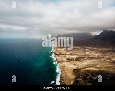 Luftaufnahme des langen Strandes Cofete in Fuerteventura mit blauem Wasser und desertischen Bergen Stockfoto