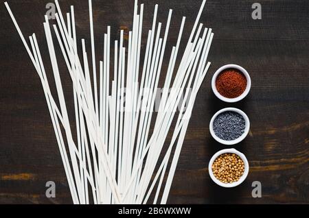 Verschiedene Gewürze und italienische Pasta auf dunklem Hintergrund. Stockfoto