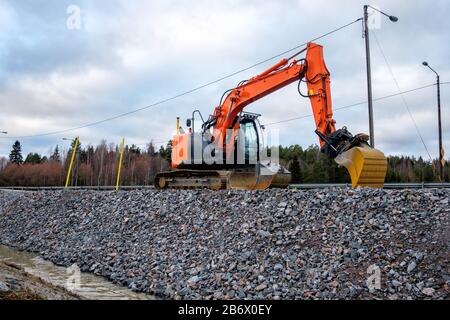 Nahaufnahme des Industriebaggers, der auf der Baustelle der Autobahn arbeitet. Stockfoto