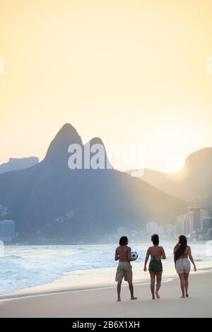 Eine Gruppe lokaler Freunde, die am Strand von Ipanema in Rio de Janeiro spazieren gehen Stockfoto