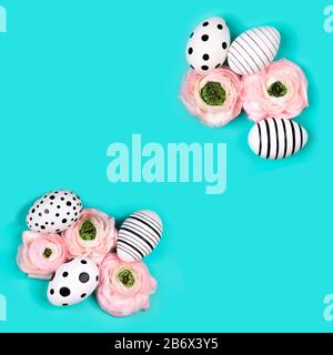Rahmen aus handgemalten Eiern und Ranunculus-Blumen auf blauem Pastellgrund. Osterkonzept. Stockfoto