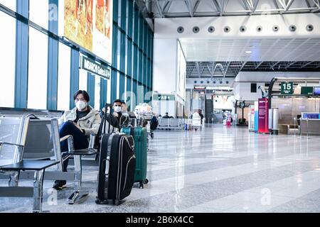 Flughafen Mailand Malpensa, Italien. März 2020. Passagiere, die im leeren Abflugterminal des Flughafens Malpensa (MXP) Gesichtsschutzmasken tragen. US-Präsident Trump hat die Reise aus Europa (außer Großbritannien) 30 Tage lang ausgesetzt, da Coronavirus Angst vor Ausbrüchen hat. Credit: Piero Cruciatti/Alamy Live News Stockfoto