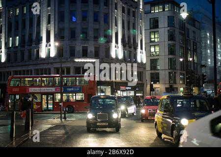 London, Großbritannien - febryary 15 2020: Londoner Nachtleben. Reflexionen auf nasser Fahrbahn von Taxis und Bussen. Zentriert Stockfoto