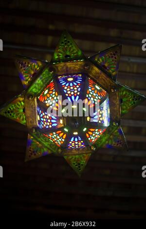 Eine bunte, traditionelle Glaslaterne, die an einer Decke in einem Haus in Fes, Morroco, hängt Stockfoto