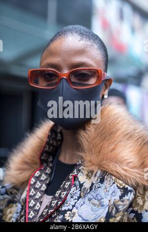 London, Großbritannien - febryary 15 2020: Modische Menschen auf der Straße . Straßenstil. Mädchen in einem braunen Anzug und einer medizinischen Maske, verteidigt sich von einem Coronovir Stockfoto