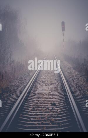 Die Perspektive der Bahngleise verschwindet morgens in Nebel Stockfoto