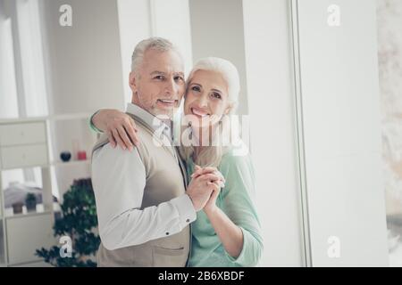 Nahaufnahme von netten alten Leuten, die gekleidetes Hemd braun türkis Pullover in einer hellen Wohnung stehen Stockfoto