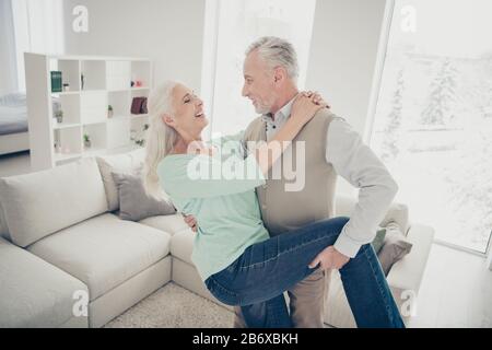 Porträt der fröhlichen lieblichen Ehepartner in der Wohnung lachend Jeans Denim Hose Teal braun Pullover Stockfoto