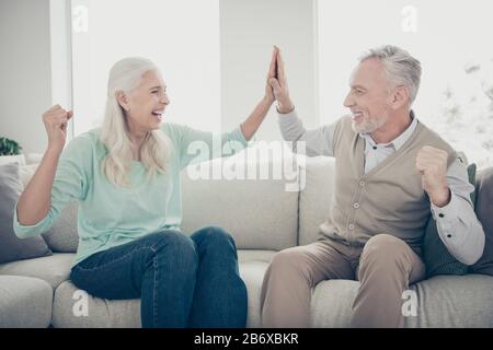 Portrait der netten Großeltern geben fünf feiern gekleidete Teelbraune Pullover Jeans Hose sitzt gemütlicher Divan Schrei in Wohnung drinnen Stockfoto
