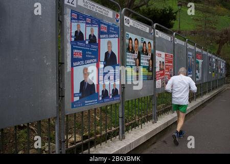 Man jogiert durch Anzeigetafeln, die Wahlkandidaten zeigen, die bei französischen Kommunalwahlen kandidieren, rue Ronsard, 75018 Paris, Frankreich, März 2020 Stockfoto