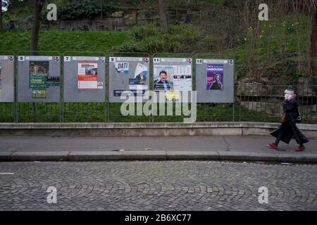 Frau geht zu Panels, die Wahlkandidaten zeigen, die bei französischen Kommunalwahlen, rue Ronsard, 75018 Paris, Frankreich, März 2020, kandidieren Stockfoto