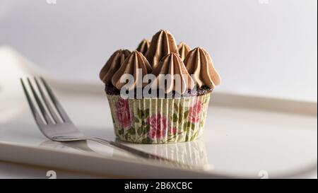 Cupcake mit Schokoladenvereisung und weißem Backgroun Stockfoto