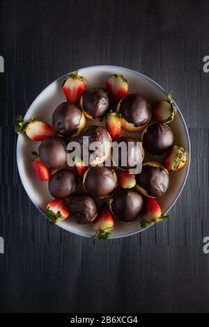 Schokoladenekullerinen mit Erdbeeren in Schale auf dunklem Hintergrund Stockfoto